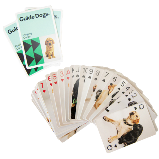 Image of a deck of playing cards fanned out featuring pictures of puppies, with two cards labeled "Guide Dogs" on top.