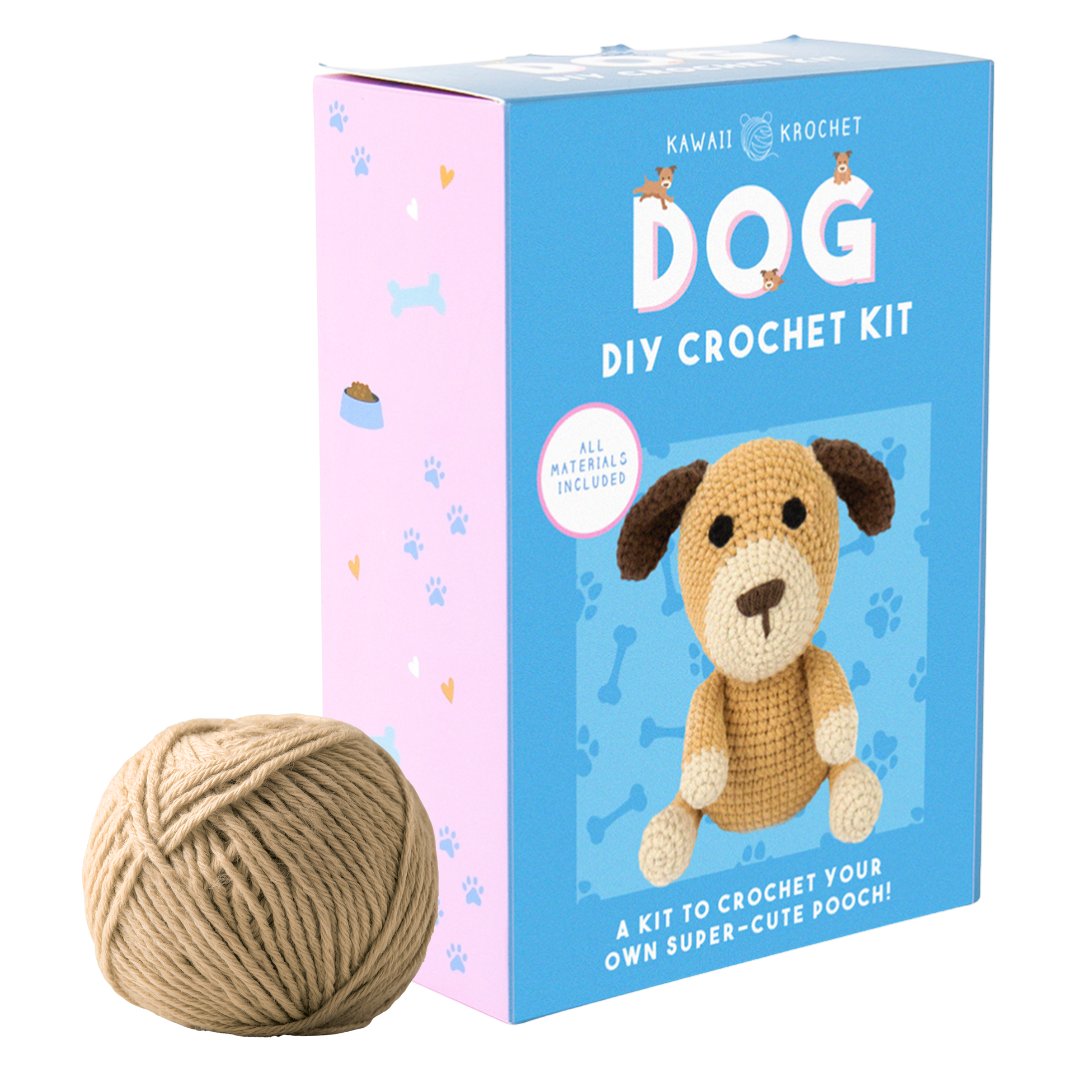 Image of a beginner crochet kit box with a cute dog design and a ball of tan yarn beside it. The blue and pink package is labeled “Crochet Kit – A kit to make your own adorable pooch!”.