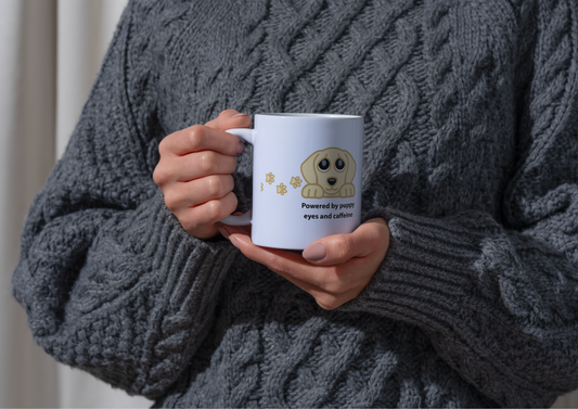 Image of a person wearing a chunky gray cable-knit sweater holds a white ceramic mug with a cartoon golden retriever and the text 'Powered by pure eyes and affection'.