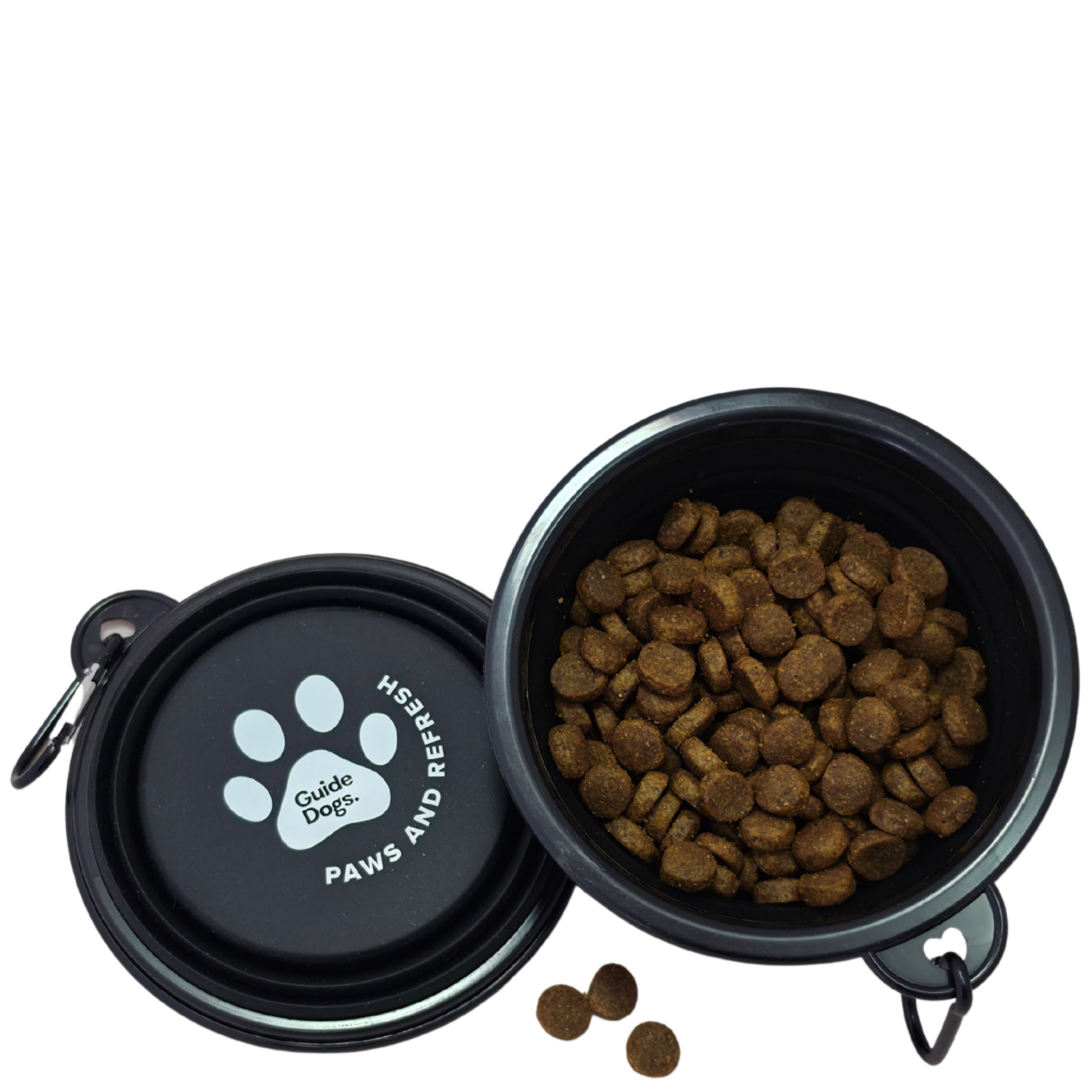 Image shows a black collapsible pet bowl shown open with kibble inside, alongside the matching lid. The lid has a white paw print and the text 'Guide Dogs' and 'PAWS AND REFRESH.