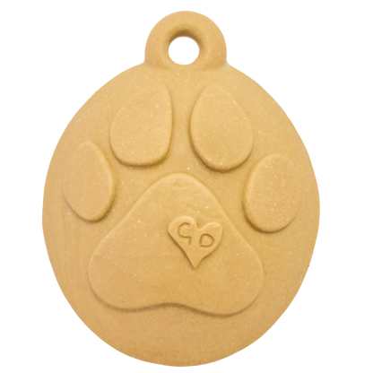 Image of Beige oval ceramic Christmas ornament with raised paw print and GD heart—ideal as a handcrafted pet keepsake.
