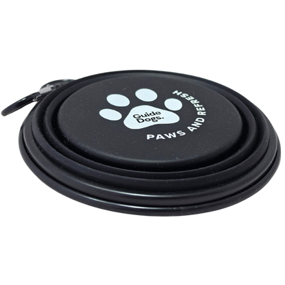 Image of a black collapsible dog water bowl with a carrying loop, featuring a white paw print logo and the text 'Guide Dogs' and 'PAWS AND REFRESH' on the base, shown on a white background.