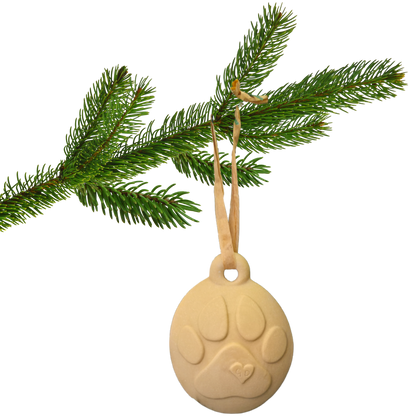 Image of A pine branch holds a Christmas Ornament—a beige ceramic dog with paw print and ribbon loop for hanging.