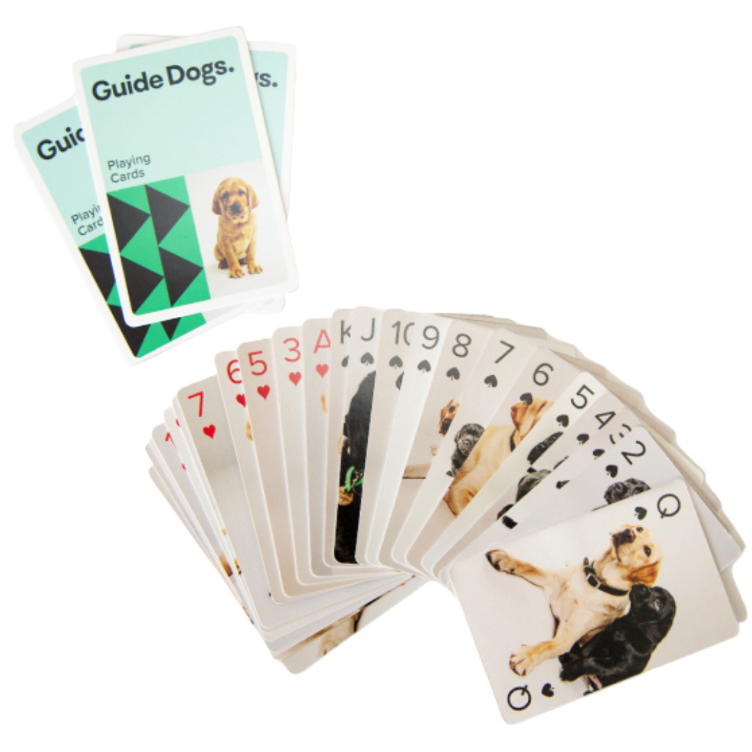 Image of a deck of playing cards fanned out featuring pictures of puppies, with two cards labeled "Guide Dogs" on top.