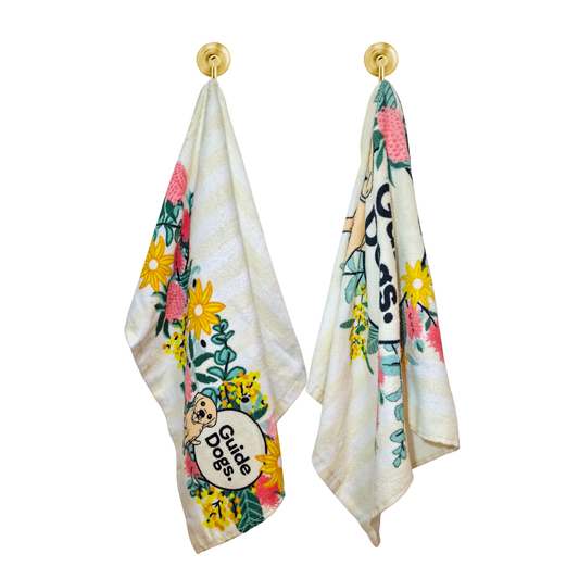 Image of two floral-themed towels with 'Guide Dogs' logo on a white background