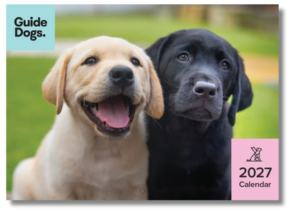 Image of a 2027 wall calendar cover featuring two Labrador retriever puppies outdoors on a grassy background, with the Guide Dogs logo in the top-left and a pink '2027 Calendar' label in the bottom-right.