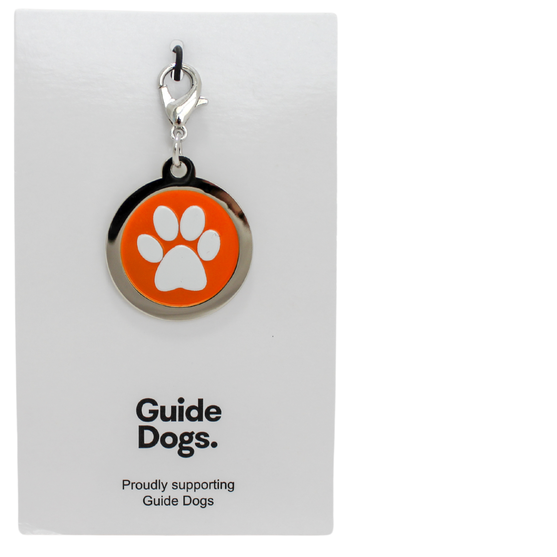 Image of a round metal charm with a white paw print on an orange background. on a card reading Guide Dogs.