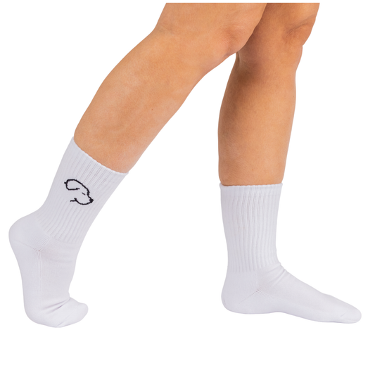 Image of person wearing white crew, socks. One with a simple dog outline at the ankle, standing on tiptoe against a white background.