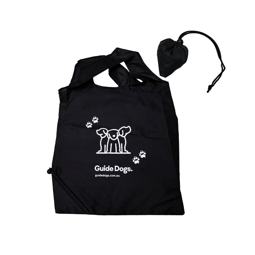 Image of a black shopping bag with white Guide Dogs logo and paw prints, includes matching drawstring pouch.