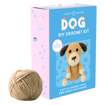 Image of a beginner crochet kit box with a cute dog design and a ball of tan yarn beside it. The blue and pink package is labeled “Crochet Kit – A kit to make your own adorable pooch!”.