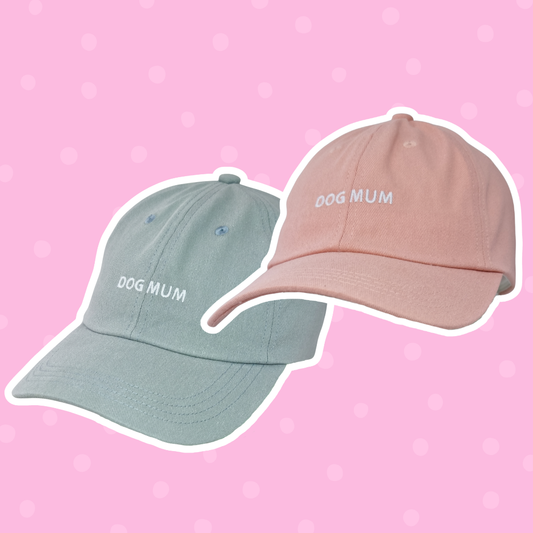 Image of two caps—one light blue, one pink with 'Dog Mum' embroidered above the brim.