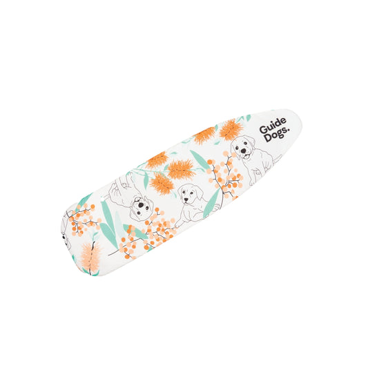 Image of the top of an ironing board. The cover has orange flowers, green leaves, cartoon guide dogs, and 'Guide Dogs' in black text.