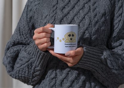 Image of a person wearing a chunky gray cable-knit sweater holds a white ceramic mug with a cartoon golden retriever and the text 'Powered by pure eyes and affection'.
