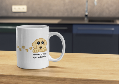 Image of a white ceramic coffee mug with a cartoon puppy graphic and the text 'Powered by puppy eyes and caffeine' sitting on a wooden countertop in a kitchen setting.