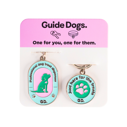 Two dog-themed keychains on a Guide Dogs packaging with pink and white background.